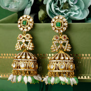 Gold and green silver earrings on a green ribbon with flowers in the background