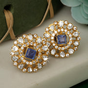 A pair of silver earrings with gold polki design and blue stones.