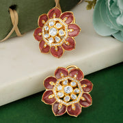 Pair of floral silver earrings with red and gold design on a green surface.