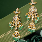 Load image into Gallery viewer, Ornate gold and green silver earrings on a green surface with floral elements.
